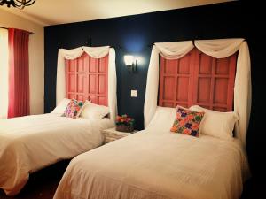 2 camas con cabeceros rojos en una habitación en María de Nadie "Hotel Boutique", en Ciudad Constitución