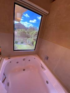 uma banheira na casa de banho com uma janela em Chalé Som da 7 Quedas Apenas 1,8km do Centro de Gonçalves MG em Gonçalves