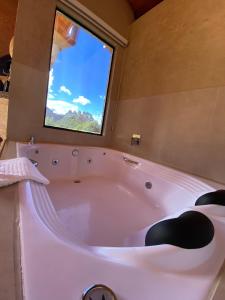 uma grande banheira branca numa casa de banho com uma janela em Chalé Som da 7 Quedas Apenas 1,8km do Centro de Gonçalves MG em Gonçalves