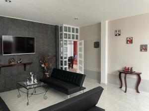 a living room with a black couch and a tv at Sensity Home Preciosa y espaciosa casa todos los servicios 5 min del CIS in Tehuacán