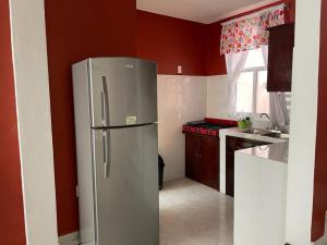a stainless steel refrigerator in a kitchen with red walls at Sensity Home Preciosa y espaciosa casa todos los servicios 5 min del CIS in Tehuacán