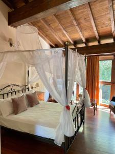 a bedroom with a canopy bed with white drapes at Aldea Couso Rural in Sarreaus