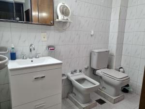 a white bathroom with a toilet and a sink at La casa de Chiqui in Mendoza