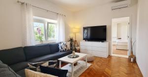 a living room with a blue couch and a tv at Sunset Apartments in Korčula