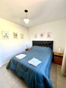 a bedroom with a blue bed with two towels on it at Lumiere Apartments - Departamento en Complejo Residencial in Mendoza