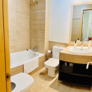 a bathroom with a toilet and a sink and a tub at Luxury Pacifico Beach in Málaga