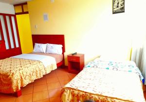 a hotel room with two beds and a table at Hospedaje Las Lilas in Huancayo