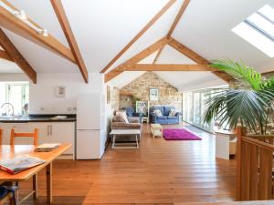 a kitchen and living room with exposed beams at The Old Barn in Penzance