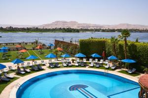 a beach with a pool, chairs, and tables at Sonesta St. George Hotel - Convention Center in Luxor