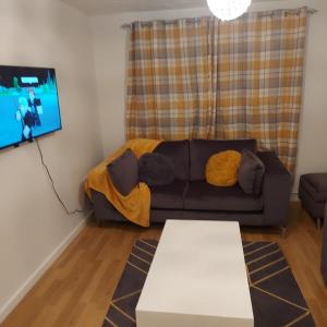 a living room with a couch and a flat screen tv at Lovely 2-Bed Apartment in Milton Keynes in Milton Keynes