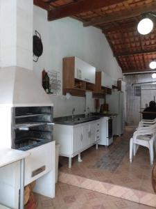 une grande cuisine avec des placards blancs et un évier dans l'établissement Chácara de Temporada - Mairiporã, à Mairiporã