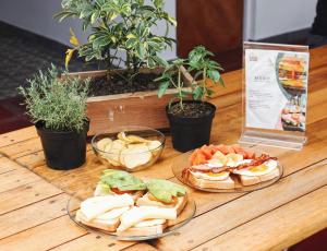 a wooden table with two plates of sandwiches and snacks at La Familia Hostel in Medellín