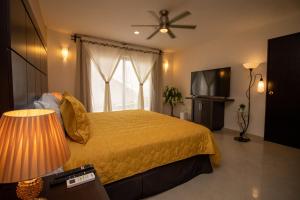 een slaapkamer met een geel bed en een televisie bij Hotel Villas Segovia Suites Playa del Carmen in Playa del Carmen
