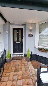 uma porta da frente de uma casa com dois vasos de plantas em The Aintree - By CHAPS em Aintree