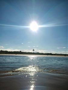 a sun is shining over a body of water at Casa temporada na praia Joia do Atlântico - Ilhéus - Ba in Ilhéus