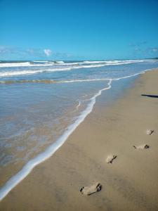 a beach with footprints in the sand and the ocean at Casa temporada na praia Joia do Atlântico - Ilhéus - Ba in Ilhéus