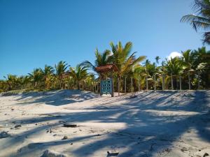 a beach with palm trees and a blue sign on it at Casa temporada na praia Joia do Atlântico - Ilhéus - Ba in Ilhéus