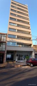 un grande edificio con un'auto rossa parcheggiata di fronte di Calle 10 - Monoambiente a La Plata