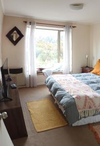 um quarto com uma cama e uma grande janela em Acogedor Apartamento, rodeado de Naturaleza y Mar. em Puerto Montt