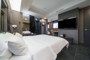 Starhills Hotel في سول: غرفة نوم بسرير ابيض كبير وتلفزيون