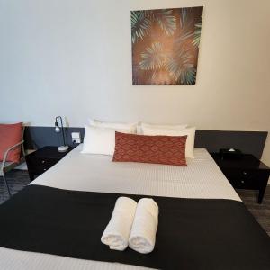 una camera da letto con un letto e due asciugamani di ZED MOTELS Tropical Gateway a Rockhampton