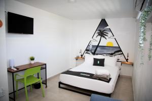 a bedroom with a bed and a desk with a palm tree on the wall at Nomada Beach Hostel- Isla Verde in San Juan