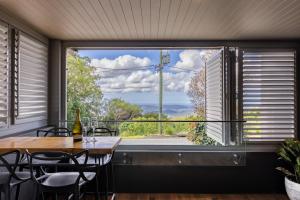 uma sala de jantar com uma mesa e uma grande janela em Luxury Hinterland Retreat - Family Suite with Hinterland and Ocean Views em Montville