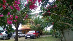 a red car parked in front of a house with flowers at Casa temporada na praia Joia do Atlântico - Ilhéus - Ba in Ilhéus