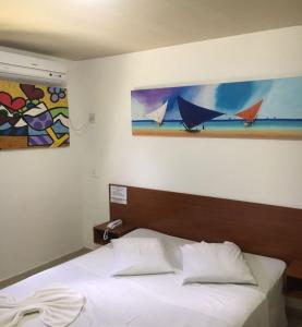 a bed in a bedroom with a painting on the wall at Pousada Beija Flor in Natal