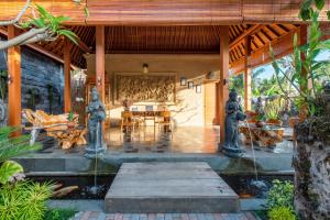 une terrasse couverte d'une maison avec des statues. dans l'établissement GK Bali Resort, à Tegalalang