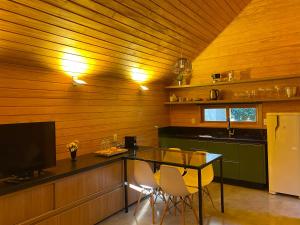 cocina con paredes de madera, mesa y sillas en Cabana I com Banheira Hidro e Lareira - Chalet Mont Blanc - Urubici, en Urubici