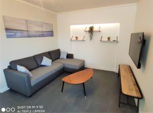 a living room with a couch and a table at Maison des Pommiers - Bord de mer et campagne in Port-en-Bessin-Huppain