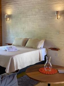 um quarto com uma cama e uma mesa com um vaso em Chalé Som da 7 Quedas Apenas 1,8km do Centro de Gonçalves MG em Gonçalves