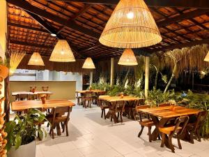 a restaurant with wooden tables and chairs and lights at Kaçuá Milagres in São Miguel dos Milagres