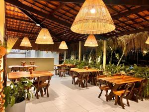 um restaurante com mesas e cadeiras de madeira e luzes em Kaçuá Milagres em São Miguel dos Milagres