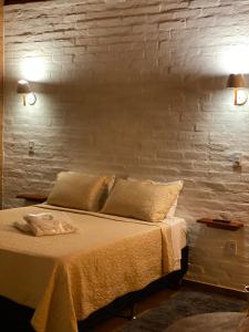 um quarto com uma cama com 2 candeeiros e uma parede de tijolos em Chalé Som da 7 Quedas Apenas 1,8km do Centro de Gonçalves MG em Gonçalves