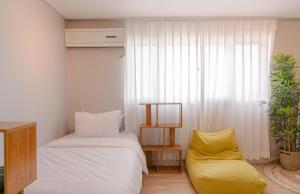 1 dormitorio con 1 cama y 1 silla amarilla en Seoul station 4min, perfect for family, en Seúl