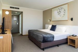 a hotel room with a bed and a flat screen tv at Pacific Hotel Cairns in Cairns