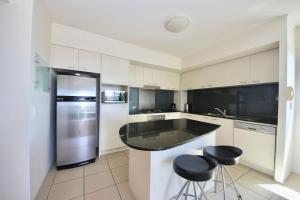 a kitchen with a refrigerator and two stools in it at BB on the Park 502 in Gold Coast