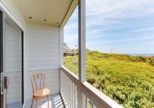 a chair on a porch with a view of the ocean at Dunescape Villas by TO in Atlantic Beach