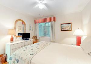 a white bedroom with a bed and a television at Dunescape Villas by TO in Atlantic Beach
