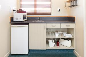 a kitchen with a counter with a sink and a microwave at Wine Country Motel Havelock North in Havelock North