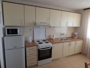 kuchnia z białymi urządzeniami i białą lodówką w obiekcie Apartments by the sea Okrug Donji, Ciovo - 17078 w mieście Okrug Donji