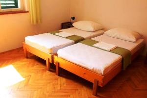 two twin beds in a room with wooden floors at Apartments with a parking space Murter - 17059 in Murter