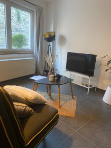 a living room with a couch and a table and a tv at Le gîte de Giulia in Dinant