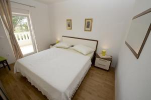 1 dormitorio con cama blanca y ventana en Apartments by the sea Promajna, Makarska - 17160, en Promajna