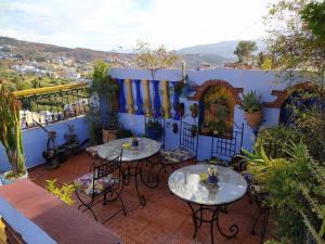 2 mesas y sillas en un patio con una pared azul en Hotel Gernika, en Chefchaouen