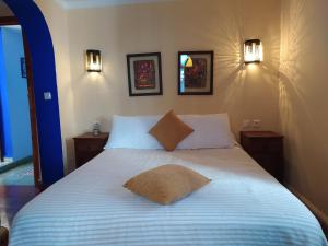 a bed in a bedroom with two lights on the wall at Hotel Gernika in Chefchaouene