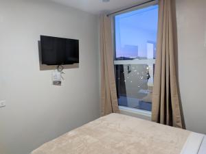 D' Loft Iligan في Iligan: غرفة نوم بسرير وتلفزيون ونافذة