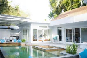a white house with a swimming pool in front of it at Tropik Resort Lombok in Selong Belanak